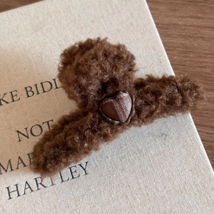 Détail de pince à cheveux en peluche marron avec cœur à carreaux et texture douce