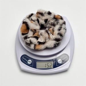 Vue détaillée d'un chouchou en peluche à motif léopard sur une balance pesant 15,2g de confort