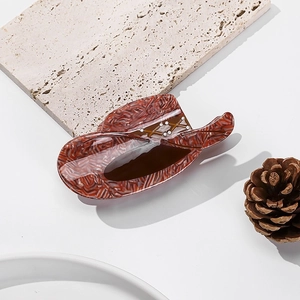 Detailed view of a unique red and white marble cowboy hat hair claw on stone surface