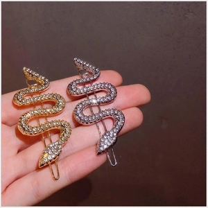 Gros plan de pinces à cheveux en forme de serpent dorées et argentées avec strass brillants