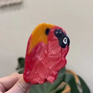 Detail of red parrot hair claw clip made of marble texture acetate with bird design