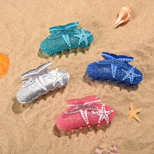 Pinces à cheveux étoile de mer avec strass en quatre couleurs sur sable de plage