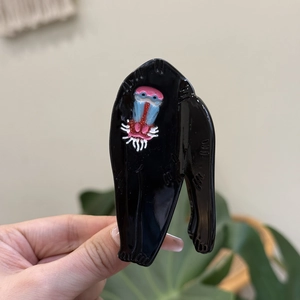 Detail of the acetate shark hair claw showing creative mandrill animal design and glossy finish
