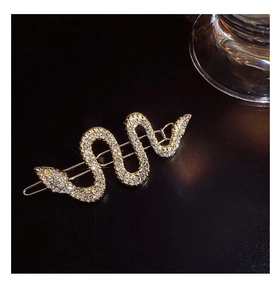 Gros plan d'une pince à cheveux serpent dorée avec des strass blancs scintillants