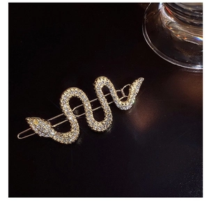 Barrette à cheveux serpent dorée étincelante avec strass sur un fond noir texturé élégant