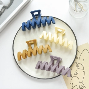 Detailed view of matte geometric shark hair clips in Morandi colors on a white plate