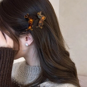 Detail of dog-shaped acetate hair clip with tortoiseshell texture on model's hair
