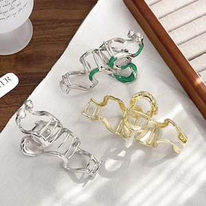 Elegant gold and silver snake hair claws on textured fabric with soft window light