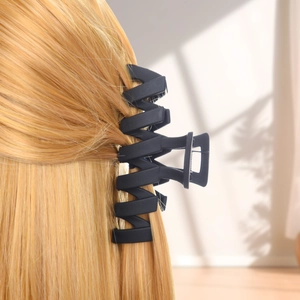 Matte black hollow shark clip with large wave teeth holding long blonde hair