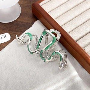 Macro shot of silver metal snake hair claw clip with green enamel detail on fabric