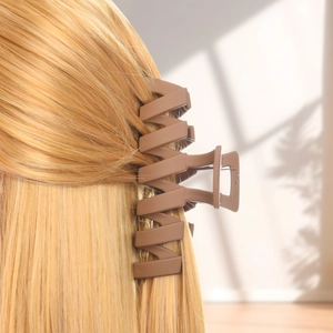 Detail of a large matte brown shark hair claw clip holding long blonde hair in a ponytail