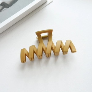 Macro shot of mustard yellow matte shark hair clip with a stylish wavy hollow design