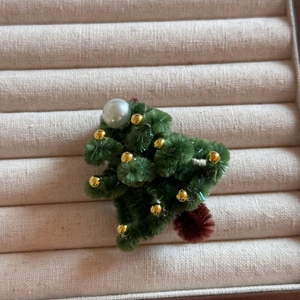 Gros plan sur l'épingle à cheveux sapin de Noël fait main avec perles sur plateau beige