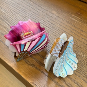 Elegant shell-shaped acetate hair claw clips with colorful rhinestones on wood background