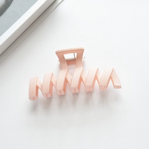 Close-up of peach matte claw clip with geometric hollow design and metal spring