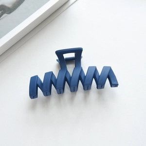 Detail of navy blue matte hair claw clip with wave pattern and strong metal spring