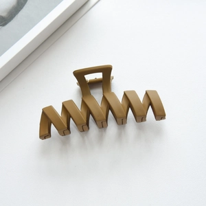 Close-up of a large matte khaki wave hair claw clip for thick hair styling