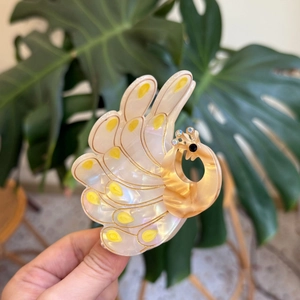 Detail of peacock hair claw showing pearl white acetate and gold wire accents