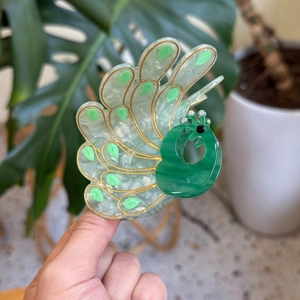 Close-up of elegant peacock acetate hair claw clip with emerald green marble texture