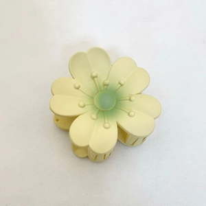 Gros plan sur la pince à cheveux tournesol jaune et vert sur fond de tissu blanc