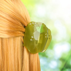 Détail d'une pince à cheveux citrouille en acétate vert avec strass sur cheveux orange