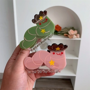 Detail showing caterpillar hair clips with cowboy hats in green and pink colors