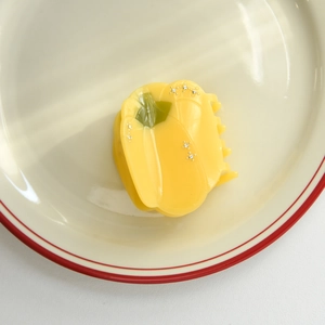 Détail de la pince à cheveux poivron jaune avec strass sur assiette céramique