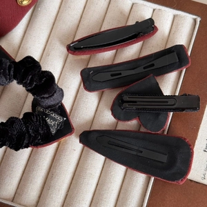 Detailed back view of red velvet hair clips and scrunchie set on a beige jewelry display