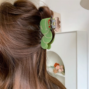 Cute green caterpillar acetate hair claw clip worn on brunette hair in modern setting