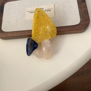 Détail d'une pince à cheveux champignon avec texture marbrée et strass jaunes brillants