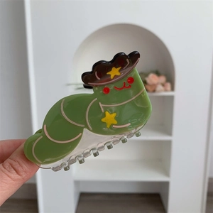 Close-up of creative green caterpillar hair claw clip made of glossy acetate material