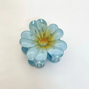 Pince à cheveux fleur tournesol bleu dégradé avec étamine orange sur fond blanc