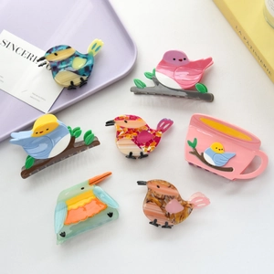 Detailed view of colorful acetate bird hair claws and coffee cup clip on a white background