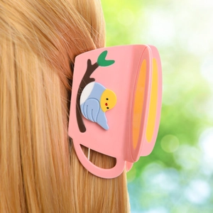 Detail showing the bird and coffee cup acetate hair claw clip worn on blonde wavy hair