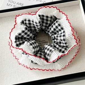 Detailed macro view of black and white checkered hair scrunchie with red wavy lace trim