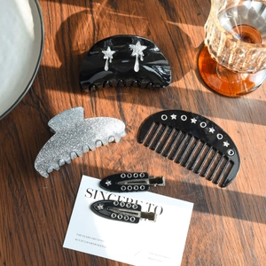 Detailed set of premium black acetate hair claws and clips on a textured wooden surface