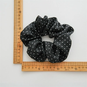 Vue détaillée d'un chouchou noir à pois avec des règles de mesure montrant sa taille