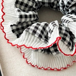 Detail of checkered hair scrunchie with white pleated edges and red contrast stitching