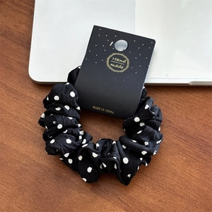 Détail d'un chouchou à pois noirs et blancs avec étiquette sur un bureau en bois brun