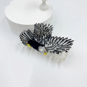 Détail de la pince à cheveux aigle créative avec plumes noires et blanches et bec jaune