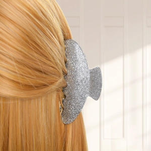 Close-up of a large silver glitter hair claw clip styling long orange hair from a side view