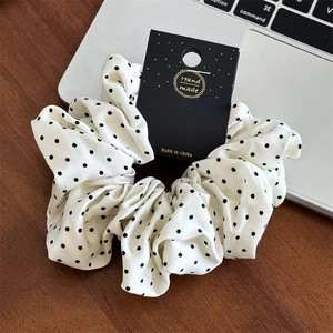 Vue détaillée du chouchou à pois fait main avec texture en mousseline et emballage de marque