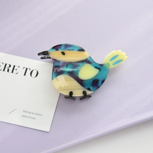 Detail shot of a bird-shaped acetate hair claw clip with blue and purple marbled textures