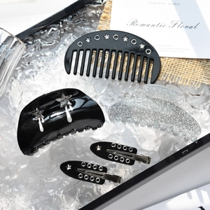 Detailed set of black and silver star hair clips and claw clips on a glass tray