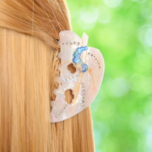 Leaf-shaped acetate hair claw with rhinestones and blue butterfly on blonde hair