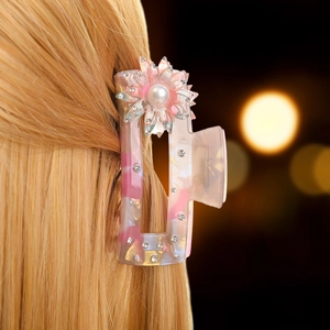 Dettaglio molletta per capelli in marmo rosa con fiore di perla su capelli biondi