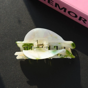 Detail of leaf pattern hair claw clip with rhinestones and green resin marble texture