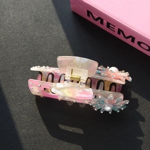 Dettaglio macro del fermaglio per capelli con fiori rosa, strass e perle lucide
