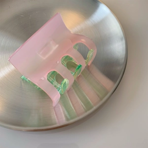 Pink acrylic checkered shark hair claw clip displayed on a brushed metal tray