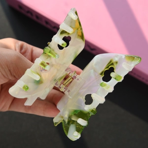 Detail view of a marble-textured butterfly hair claw with white and green acetate finish